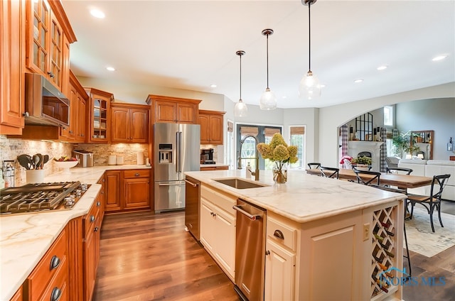 kitchen featuring stainless steel appliances, sink, dark hardwood / wood-style floors, a center island with sink, and a breakfast bar