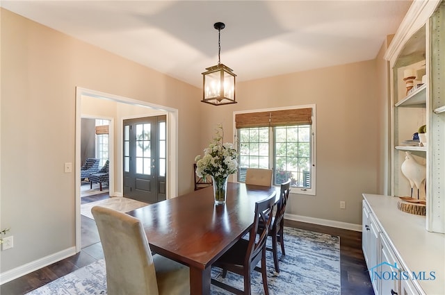 dining area with dark wood-type flooring and a notable chandelier