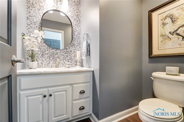 bathroom featuring hardwood / wood-style floors, toilet, decorative backsplash, and vanity