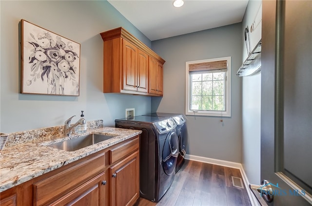 clothes washing area featuring separate washer and dryer, dark hardwood / wood-style flooring, cabinets, and sink