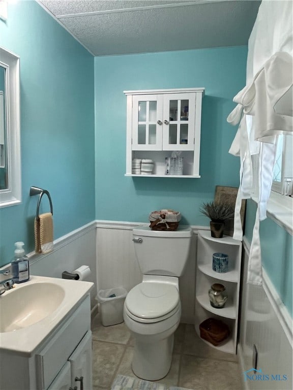 bathroom with toilet, vanity, a textured ceiling, and tile patterned floors