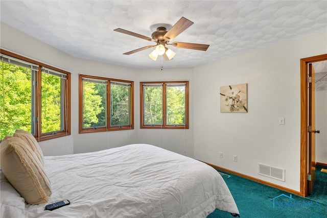 carpeted bedroom featuring multiple windows and ceiling fan