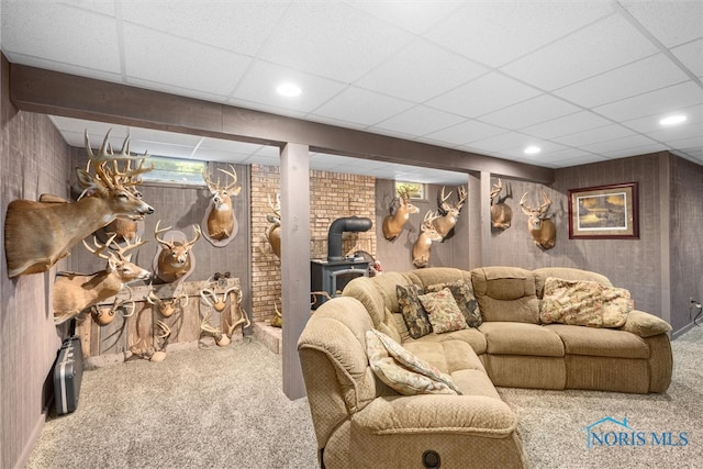 living room featuring carpet flooring, a wood stove, and a paneled ceiling