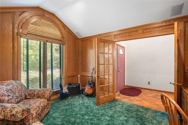 sitting room featuring wooden walls, vaulted ceiling, and parquet floors