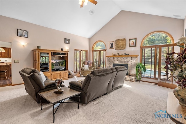 carpeted living room with a fireplace, high vaulted ceiling, and ceiling fan