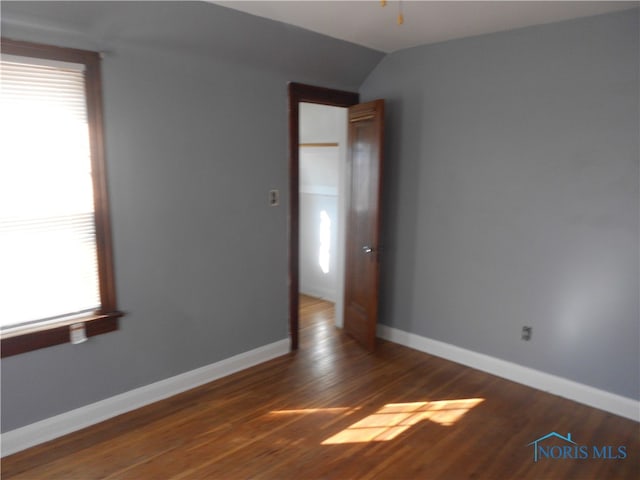 spare room with a healthy amount of sunlight, lofted ceiling, and dark hardwood / wood-style flooring