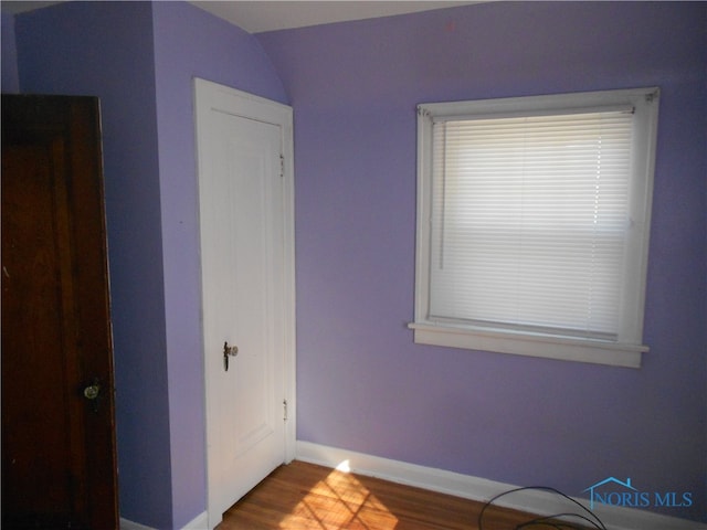 unfurnished bedroom with wood-type flooring and vaulted ceiling