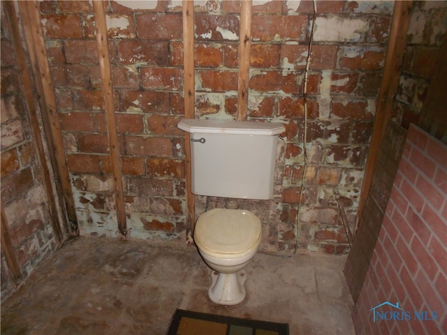 bathroom with brick wall and toilet