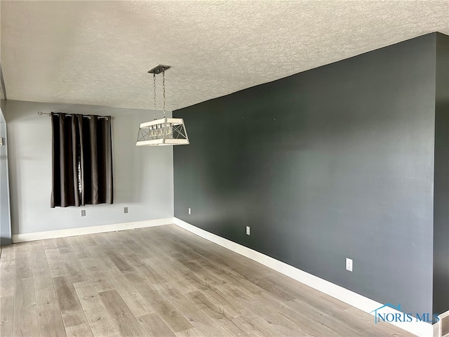 unfurnished dining area featuring light hardwood / wood-style flooring and a textured ceiling