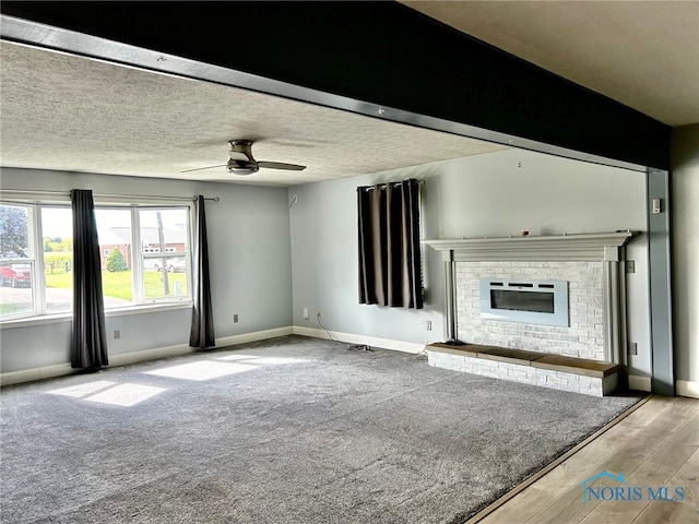 unfurnished living room with a textured ceiling, light hardwood / wood-style floors, a fireplace, and ceiling fan