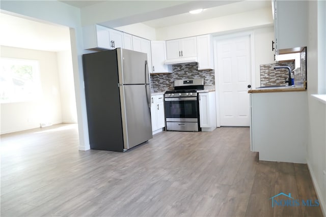 kitchen featuring white cabinetry, backsplash, stainless steel appliances, light hardwood / wood-style flooring, and sink