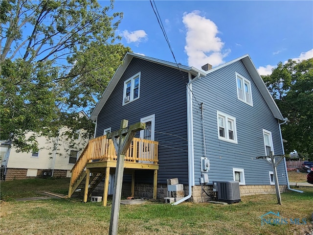 rear view of property featuring a lawn, a deck, and central air condition unit