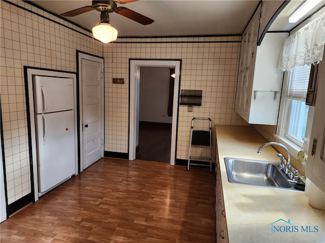 kitchen with ceiling fan, sink, dark hardwood / wood-style floors, tile walls, and white fridge