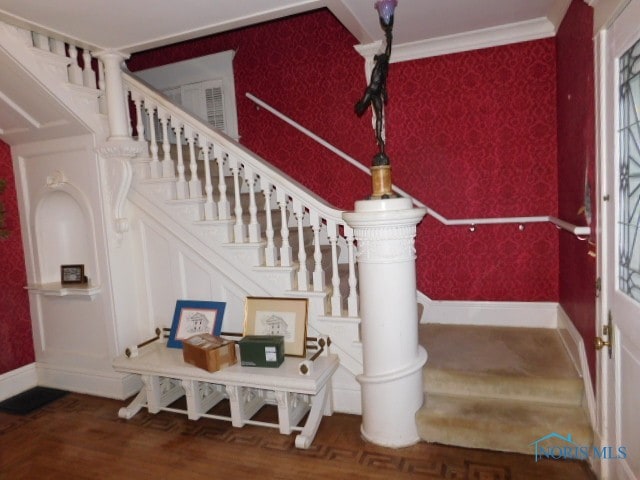 stairs with wood-type flooring and crown molding