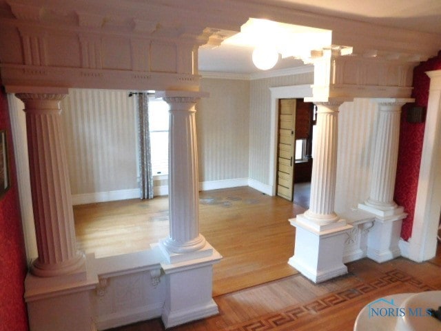 interior space with wood-type flooring, decorative columns, and ornamental molding