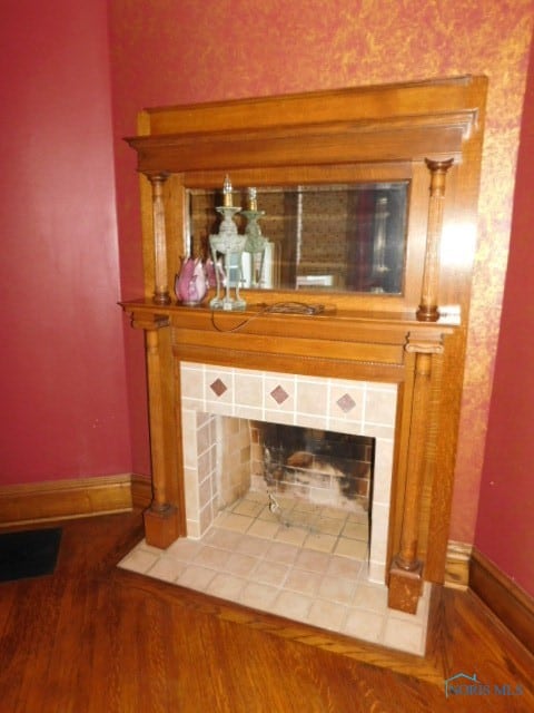 details featuring a tile fireplace, tasteful backsplash, indoor bar, and hardwood / wood-style flooring