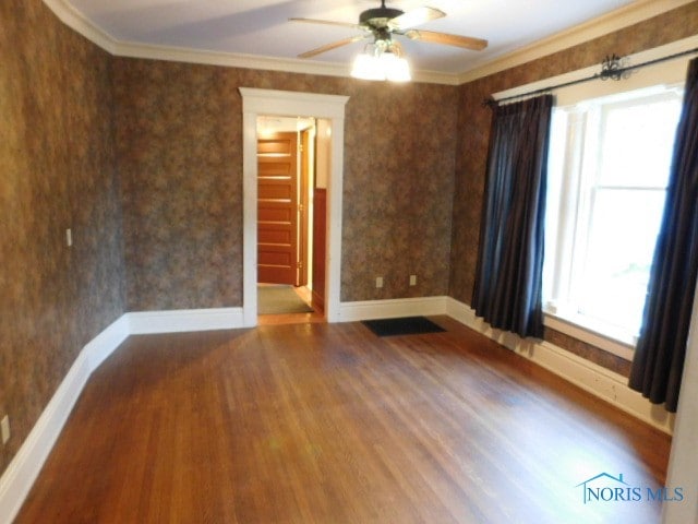 empty room with ornamental molding, hardwood / wood-style floors, and ceiling fan