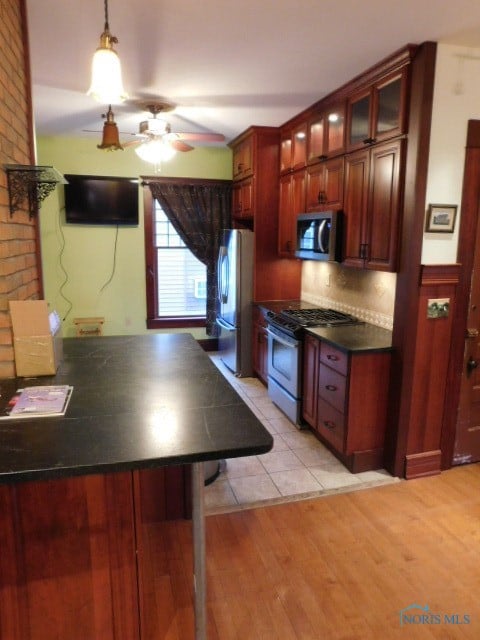 kitchen featuring ceiling fan, kitchen peninsula, backsplash, stainless steel appliances, and light wood-type flooring