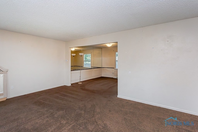 unfurnished living room featuring a textured ceiling and dark carpet