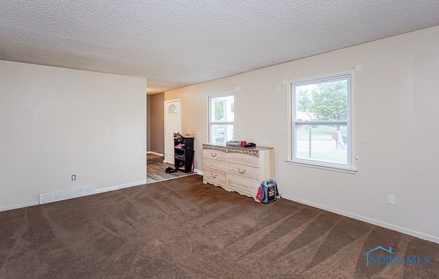 unfurnished bedroom featuring a textured ceiling and dark colored carpet