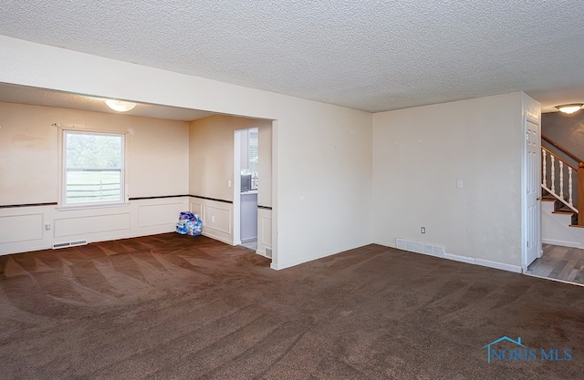 unfurnished living room with dark carpet and a textured ceiling