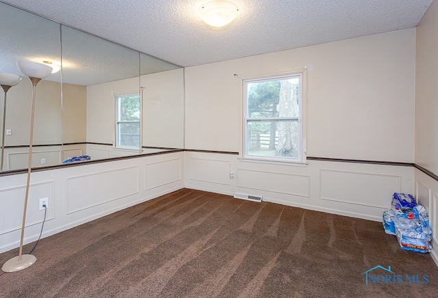 carpeted empty room featuring a textured ceiling