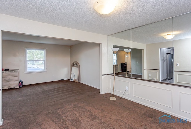 interior space featuring a textured ceiling and dark colored carpet