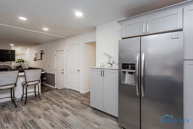 kitchen with stainless steel refrigerator with ice dispenser and hardwood / wood-style flooring