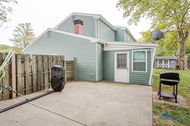 rear view of property featuring a shed and a patio