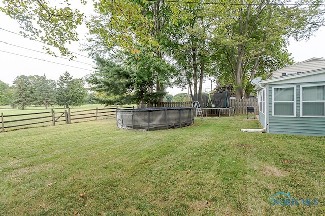 view of yard with a trampoline and a fenced in pool