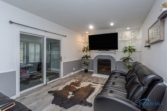 living room featuring a textured ceiling, hardwood / wood-style flooring, and a fireplace