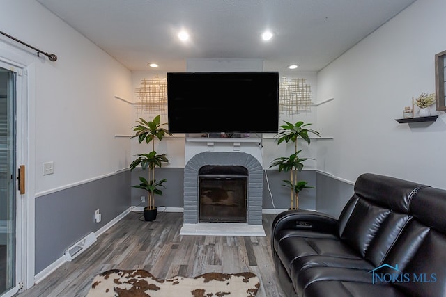 living room with a brick fireplace and hardwood / wood-style flooring