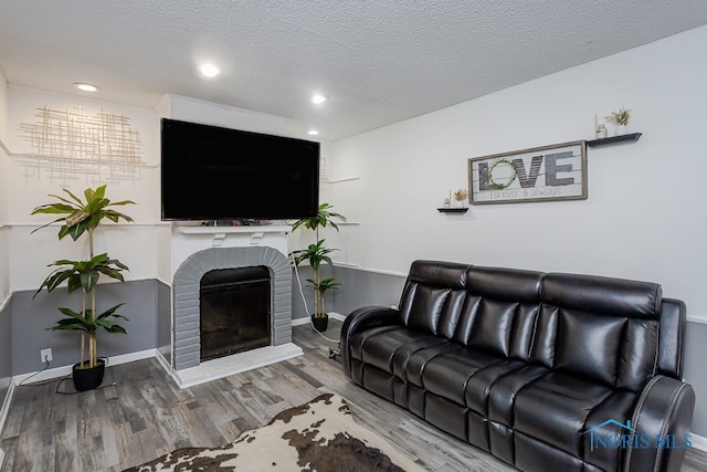 living room with hardwood / wood-style floors, a textured ceiling, and a fireplace