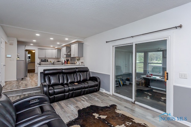 living room featuring light wood-type flooring and a textured ceiling