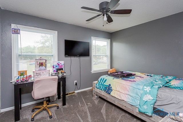 bedroom with multiple windows, dark carpet, and ceiling fan