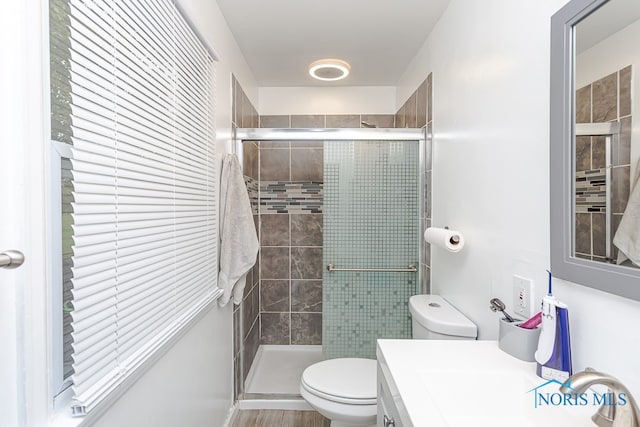 bathroom with a shower with shower door, hardwood / wood-style flooring, vanity, and toilet