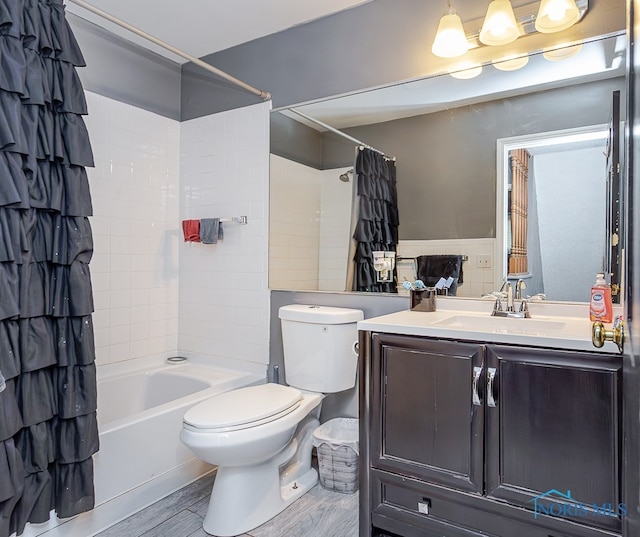 full bathroom with hardwood / wood-style floors, vanity, shower / tub combo, and toilet