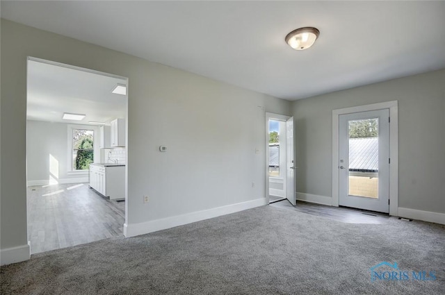 carpeted spare room with baseboards and a sink