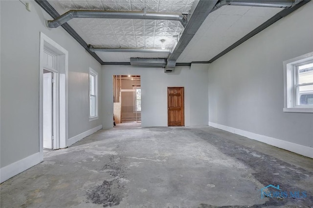 empty room featuring concrete flooring, a wealth of natural light, and baseboards