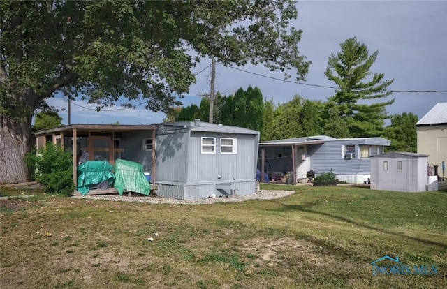 rear view of property featuring a yard, a storage unit, and an outbuilding