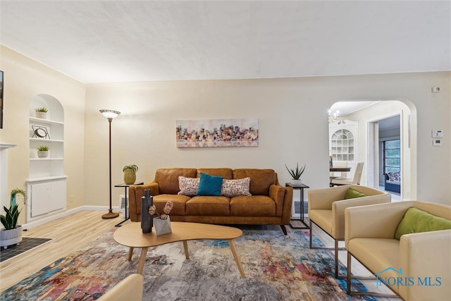 living room with built in features, a chandelier, and wood-type flooring