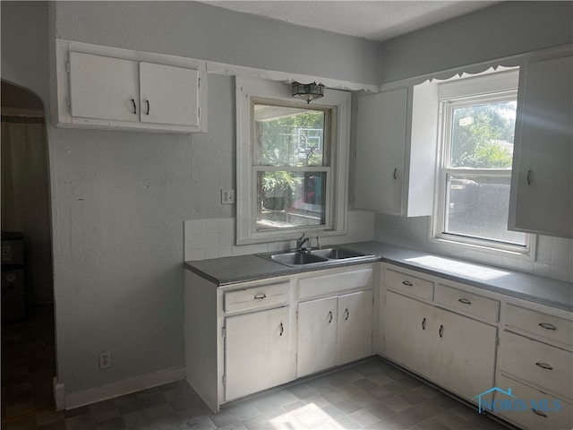 kitchen with a healthy amount of sunlight, decorative backsplash, sink, and white cabinets