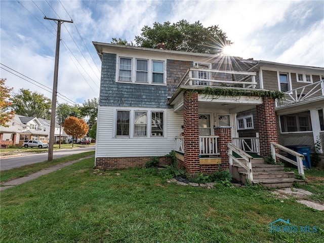 view of front of house with a front yard, a balcony, and covered porch