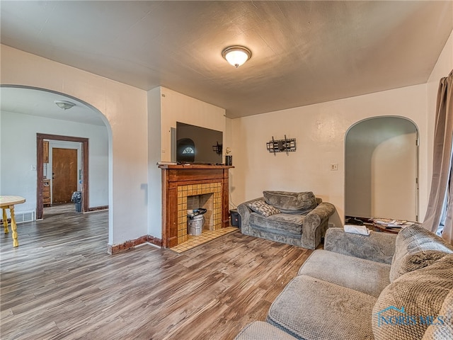 living room with wood-type flooring and a tile fireplace