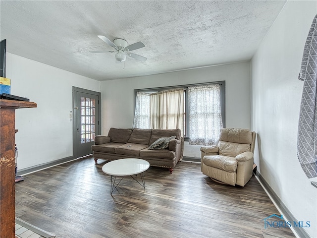 living room with a wealth of natural light, ceiling fan, a textured ceiling, and dark hardwood / wood-style flooring