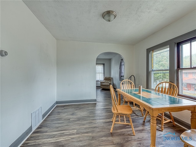 dining area with a textured ceiling and dark hardwood / wood-style flooring