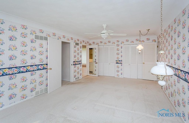 interior space featuring two closets, visible vents, and wallpapered walls