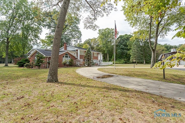 view of front facade with brick siding, a chimney, and a front yard