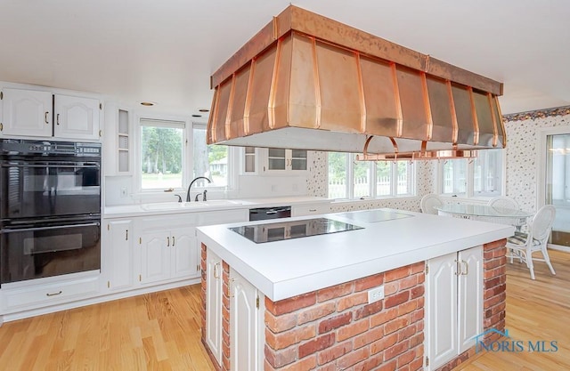 kitchen featuring a sink, white cabinetry, light countertops, black appliances, and wallpapered walls