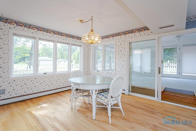 dining space with wallpapered walls, visible vents, baseboard heating, and wood finished floors